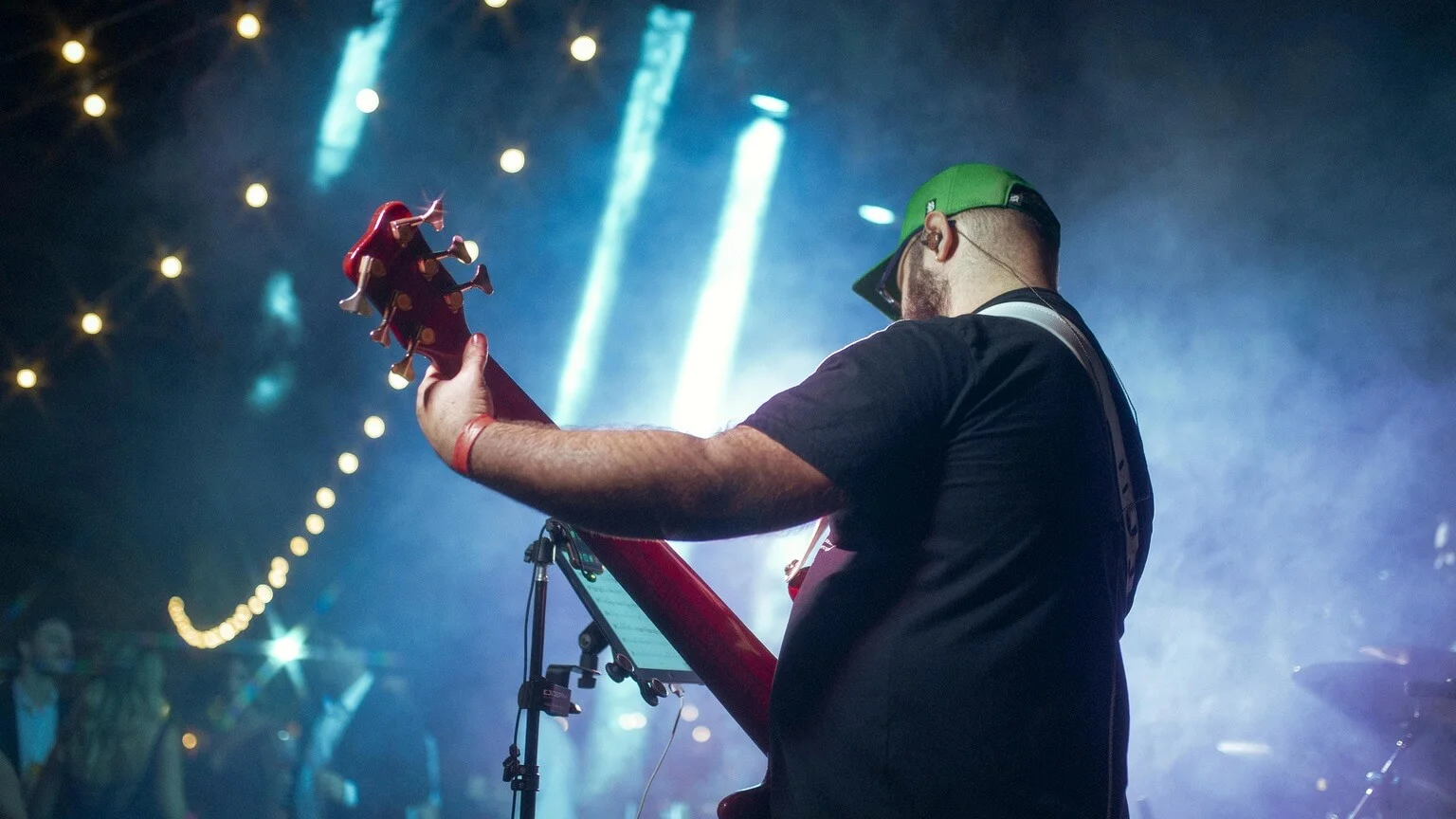 Guitarist on stage with two color-coded audio cables splitting click and backing track to separate outputs